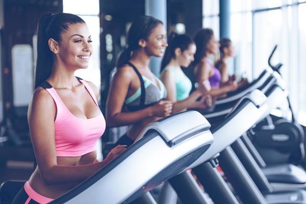 running towards their fitness goals side view of young beautiful women looking away with smile while running on treadmill at gym photo